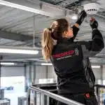 Sicherheitsdienstleistungen von Priesmeier – Technikerin bei der Montage eines Brandmelders