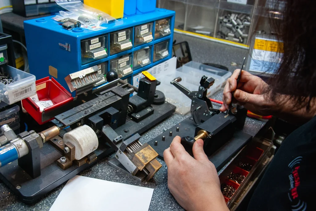 schloesser-und-schluessel-schluesselanfertigung-priesmeier Mitarbeiter bearbeitet einen Schlüssel an einer Maschine in der Priesmeier Werkstatt